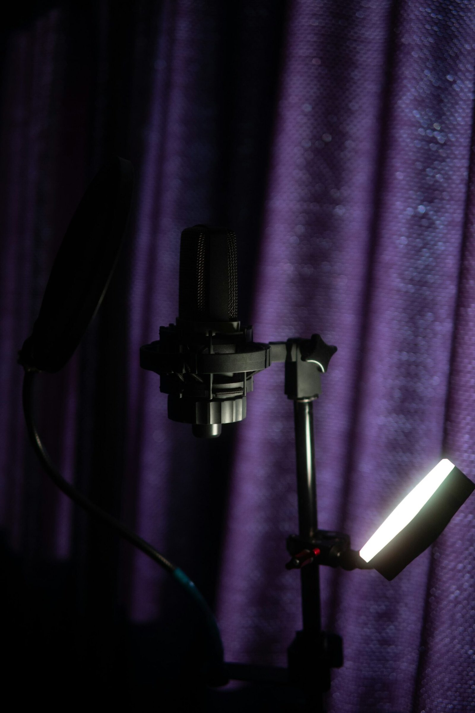 ميكروفون تسجيل احترافي أمام خلفية بنفسجية داكنة ضمن بيئة إنتاج صوتي