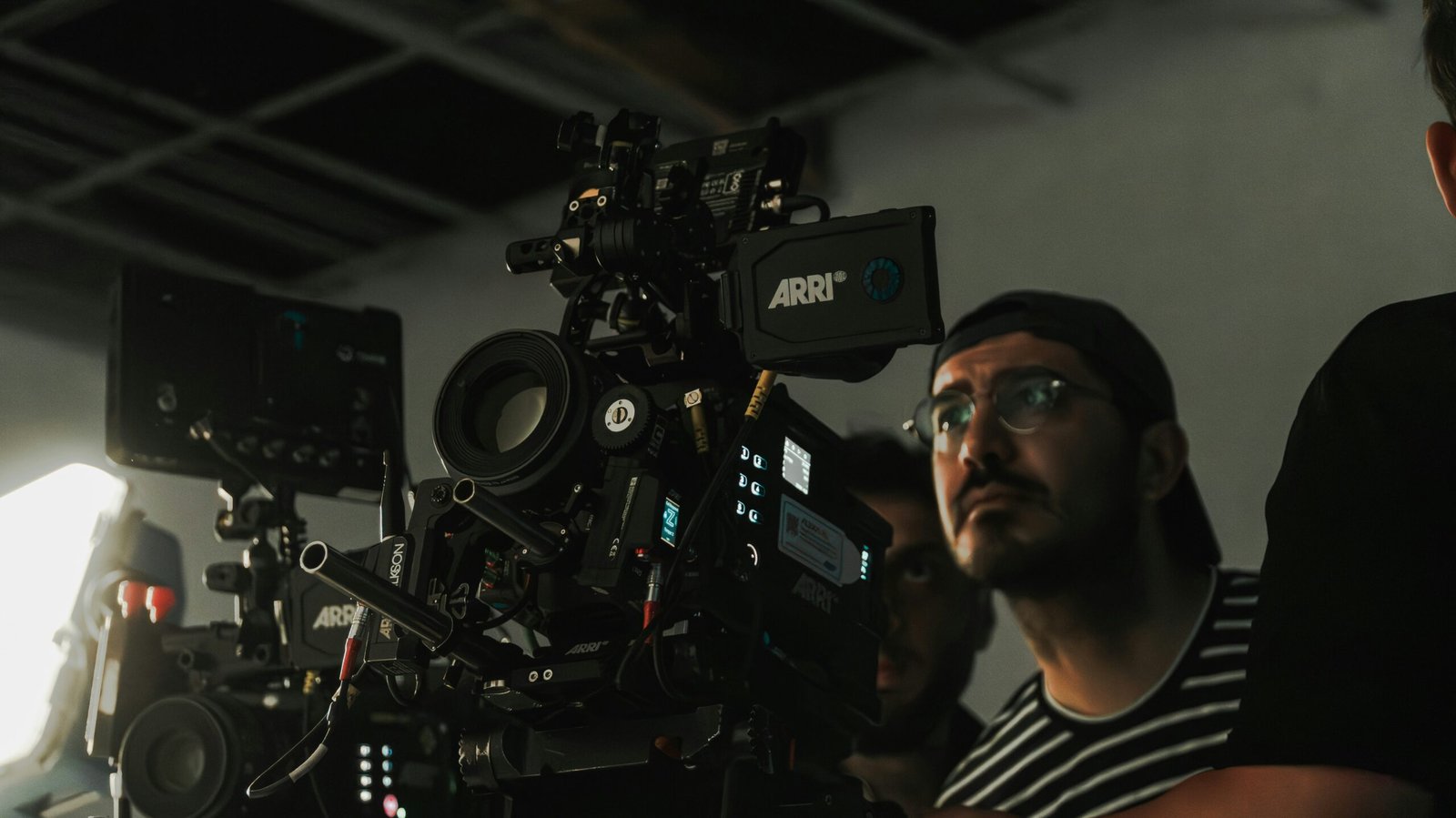 فريق تصوير يراجع إعداد كاميرا سينمائية محاطة بإضاءة الاستوديو