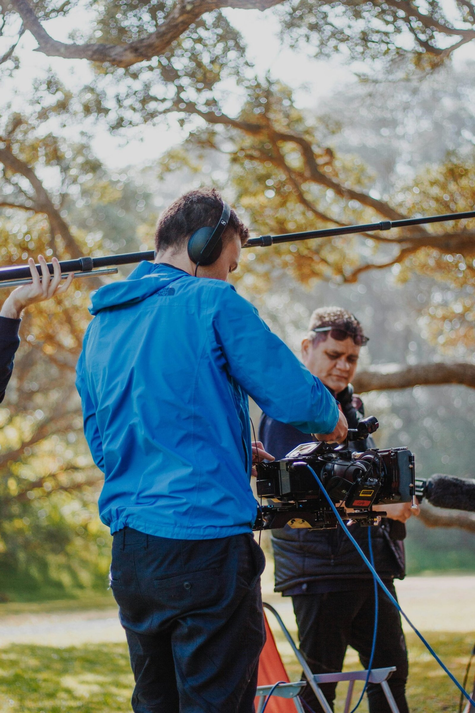 صانع أفلام يستخدم ميكروفون بوم بالقرب من الكاميرا أثناء تصوير مشهد خارجي