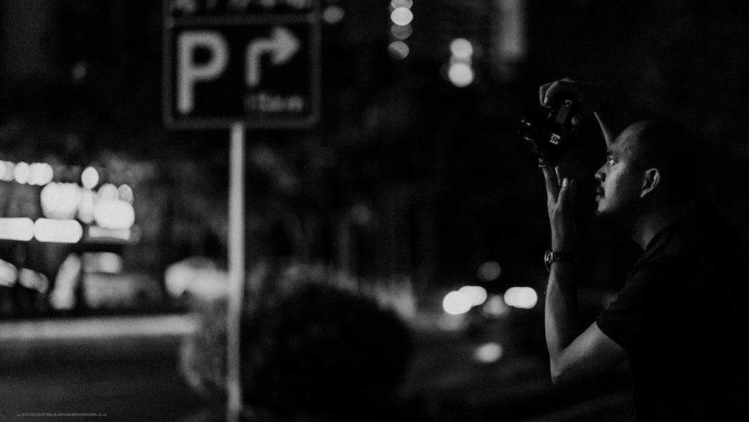 مصور يستخدم كاميرا رقمية ليلًا، مناسب لشرح أثر ISO المرتفع والتشويش على الصورة