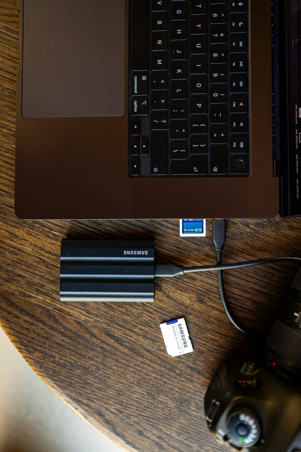 بطاقة ذاكرة وكاميرا وقرص SSD متصل بحاسوب ضمن عملية حفظ ملفات التصوير